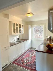 uma cozinha com armários brancos e um tapete no chão em Flott 4-roms leilighet til leie em Trondheim