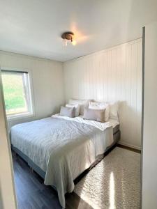 um quarto com uma cama com lençóis brancos e uma janela em Flott 4-roms leilighet til leie em Trondheim