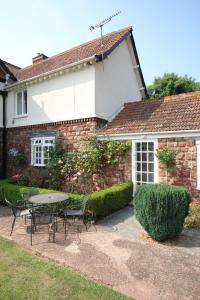 a patio with a table and chairs in front of a house at April Cottage in Minehead