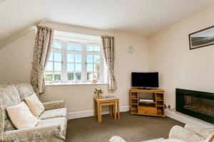 a living room with a couch and a television at April Cottage in Minehead
