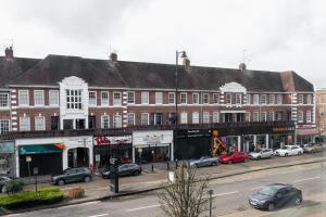 a large brick building with cars parked on a street at Skyvillion - COZY LARGE 4 & 1 Bed Apartments in London Enfield, Mins to Tube Station, Free Wi-Fi in Cockfosters