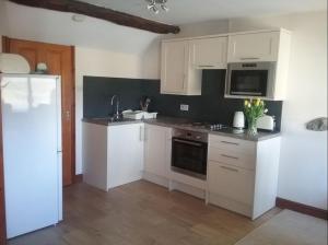 a kitchen with white cabinets and a refrigerator at Fell View Bassenthwaite in Bassenthwaite