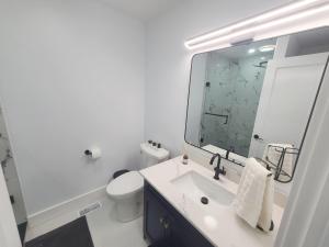 ein Badezimmer mit einem Waschbecken, einem WC und einem Spiegel in der Unterkunft Modern East York Retreat 20 mins to DT Toronto in Toronto