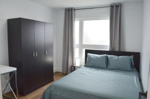 ein Schlafzimmer mit einem Bett, einem Schrank und einem Fenster in der Unterkunft Modern East York Retreat 20 mins to DT Toronto in Toronto