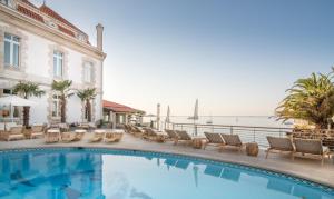 a swimming pool with chairs and the ocean in the background at The Albatroz Hotel in Cascais
