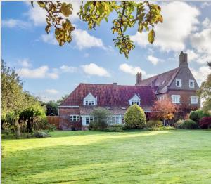 a large red brick house with a green yard at Catton Old Hall Norwich in Norwich