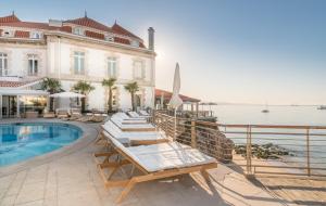 a pool with lounge chairs next to a building at The Albatroz Hotel in Cascais