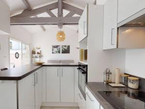 a white kitchen with white cabinets and black counter tops at Villa confortable avec piscine, proche plage, 3 chambres, grand séjour, patio, WIFI, équipement complet - FR-1-413-87 in Capbreton