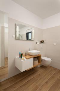 een badkamer met een wastafel, een toilet en een spiegel bij Villa Palm Bay 1, heated pool - 5 m from the sea in Ražanj