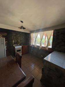 uma cozinha com uma mesa e um fogão e algumas janelas em Cabaña en los soles de montaña em Villa Pehuenia