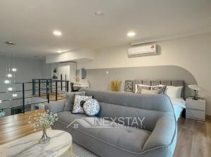 een woonkamer met een blauwe bank en een trap bij Arte Cheras KL Nordic Design Duplex by Nexstay in Kuala Lumpur