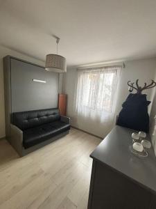 a living room with a black leather couch in a room at Maison aux Portes de Paris in Vitry-sur-Seine