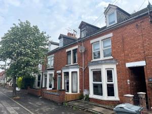 a red brick house with white windows on a street at Spacious 4 Bed House With Park Views in Lincolnshire