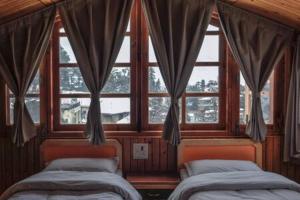 1 dormitorio con 2 camas frente a una ventana en Kalawati Homes, en Shimla