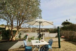 uma mesa e cadeiras com um guarda-sol num quintal em Olive Garden By Air Premier em Newhaven