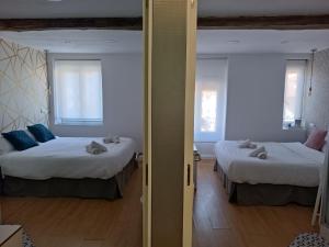 two beds in a room with two windows at Rin Rooms in Mutriku