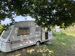 una caravana plateada estacionada en un campo bajo un árbol en Campsite with Gypsy Vardo Bell Tent, en Loré