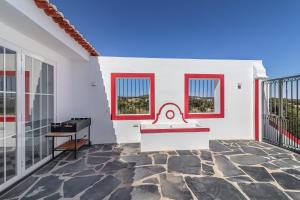 uma casa branca com janelas vermelhas e uma varanda em Monte da Vista Alegre em Elvas