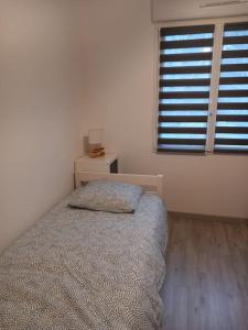 a bedroom with a bed and a nightstand and a window at Maison de la croix Marion in Chinon