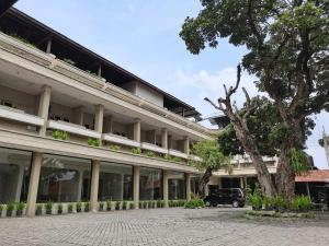 un edificio con un árbol delante de él en Hotel Catur Putra, en Magelang