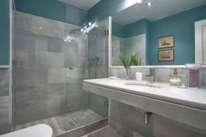 uma casa de banho com um lavatório e um chuveiro com um espelho. em Luminoso Apartamento Barrio Santa Cruz em Sevilha