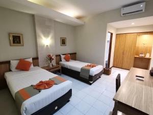 Habitación de hotel con 2 camas y mesa en Hotel Catur Putra, en Magelang