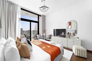 - une chambre blanche avec un grand lit et une télévision dans l'établissement Silkhaus Modern Studio near Silicon Shopping Mall, à Dubaï