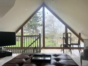 a living room with a couch and a large window at Luxurious Oak Barn in Cotswold Countryside in Shipston-on-Stour