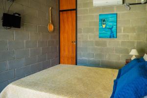 a bedroom with a bed and a television and a brick wall at Casa do Pescador Camburi in Camburi