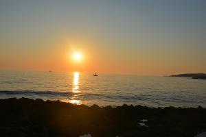 a sunset over the ocean with a boat in the water at Piccolo Hotel in Rosignano Solvay
