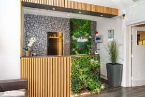 un vestíbulo con una pared verde con plantas en Croft Court Hotel, en Londres