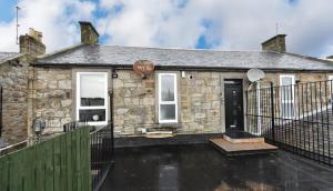 a stone house with a fence in front of it at Troon Portland Apt B in Troon