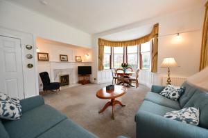 a living room with a blue couch and a table at Dunvegan Apartment Troon in Troon