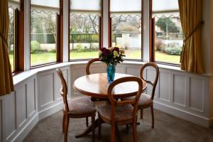 a table with chairs and a vase of flowers in a room with windows at Dunvegan Apartment Troon in Troon