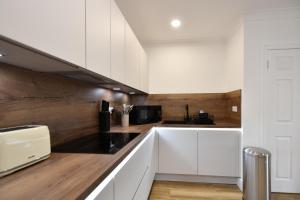 a kitchen with white cabinets and a counter top at Troon Portland Apt A in Troon