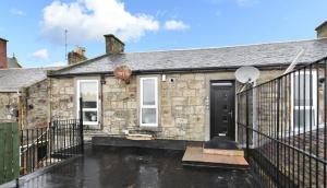 a stone house with a black door and a balcony at Troon Portland Apt A in Troon