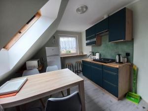 a kitchen with blue cabinets and a wooden table at Pokoje, apartament NA WYSPIE in Sobieszewo