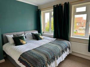 a bed in a bedroom with two windows at Comfortable 3 Bed Perfect For Contractors in Lincolnshire