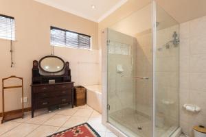 a bathroom with a shower and a sink and a mirror at House Falcon - close to ZAH in Pretoria