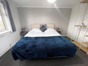 a bedroom with a large bed with a blue blanket at Comfortable Contractor Let 4bed in Lincolnshire