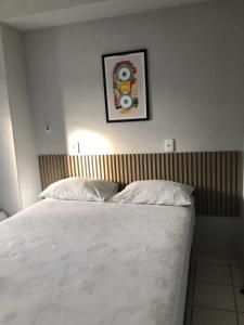 uma cama com lençóis brancos e uma foto na parede em Hotel Oiticica em Fortaleza