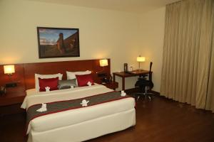 a hotel room with a large bed and a desk at The Altruist Business Hotel Hitech in Hyderabad