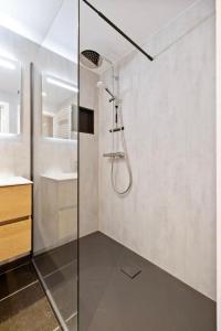 een douche met een glazen deur in de badkamer bij Beachday II met garagebox in Nieuwpoort