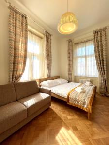 a bedroom with a bed and a couch and windows at Havelska Old Town Residence in Prague