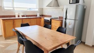 Una cocina con una mesa de madera y un refrigerador. en Linea Recta Sur- Huemul, departamento amplio, de 3 dormitorios a pasos del mar, en Puerto Madryn 29 fotos más
