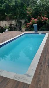 uma piscina com água azul e um deque de madeira em Casa Aconchegante em Saquarema