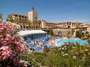 a resort with a pool with blue umbrellas and people at Villa Perle d'or vue mer in Saint-Raphaël