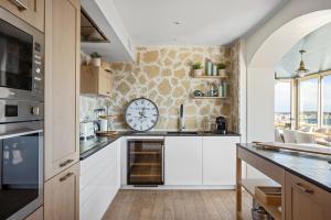 eine Küche mit weißen Schränken und einer Uhr an der Wand in der Unterkunft Villa Bastide : Sea view / Hot Tub / Sauna in Vallauris
