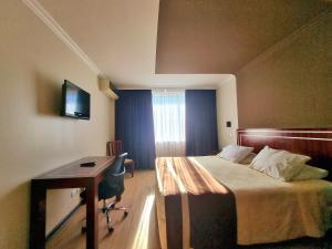 a hotel room with a bed and a desk with a computer at Hotel El Araucano in Concepción