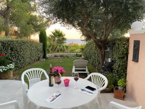 una mesa blanca con 2 sillas y una mesa con copas de vino en Villa Perle d'or vue mer en Saint-Raphaël